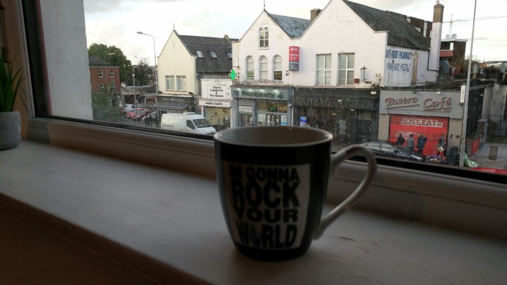 A cup of coffee on a windowsill looking out over a Dublin street