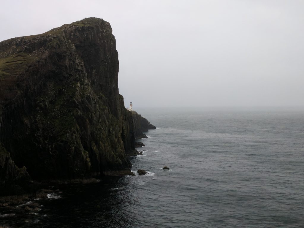 A large cliff in the foreground, and the lighthouse in the background, the Neist Point hike takes you past all of this