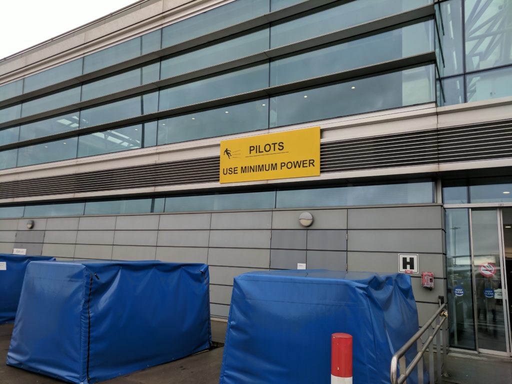 A sign at Dublin airport showing a man being blown away, and instructing pilots to use minimum power